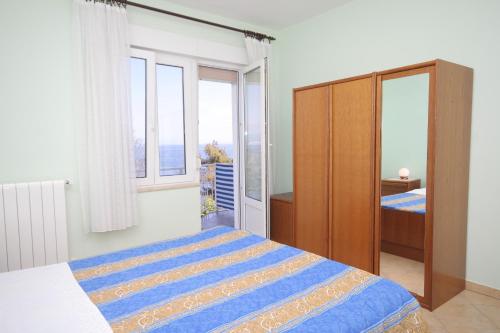 a bedroom with a bed and a cabinet and windows at Double Room Medveja 7775c in Lovran
