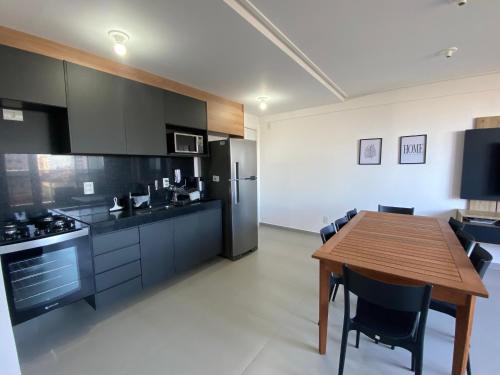 a kitchen with a wooden table and black cabinets at Villi 503C in João Pessoa