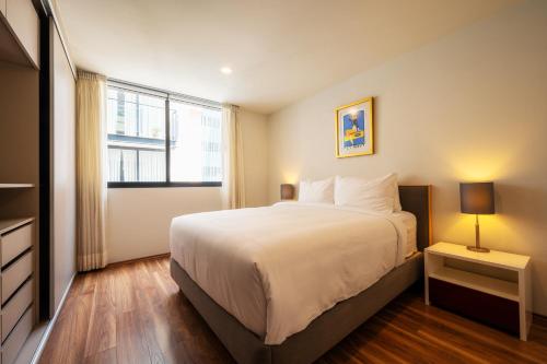 Un dormitorio con una cama grande y una ventana en Capitalia - Apartments - CÉFIRO CINCO, en Ciudad de México