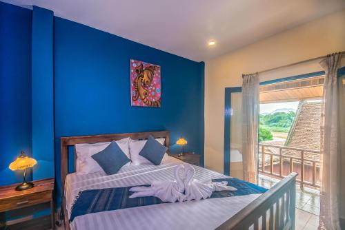 um quarto com uma cama com uma parede azul em Maison Zen Aphay em Luang Prabang