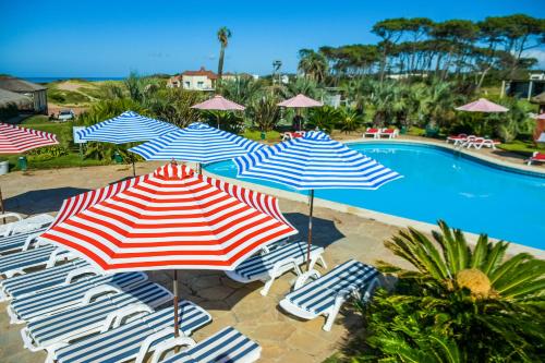 a group of umbrellas and chairs next to a swimming pool at Tio Tom - All Inclusive in Punta del Este