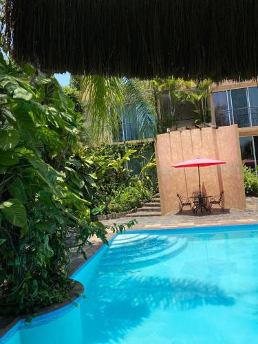 a swimming pool with a table and a red umbrella at Hotel Camino Surreal Xilitla in Xilitla