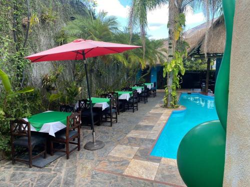 a row of tables and chairs with an umbrella next to a pool at Hotel Camino Surreal Xilitla in Xilitla