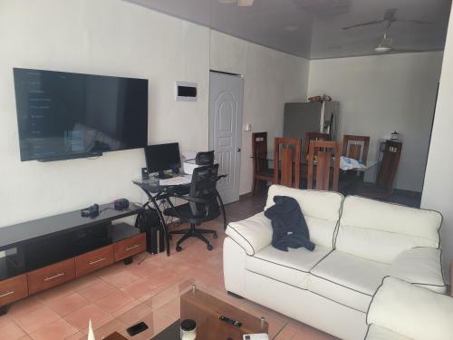 uma sala de estar com um sofá branco e uma televisão de ecrã plano em Sosua Apartment 4-Bedrooms em Sosúa