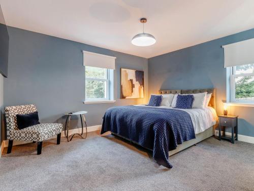 a bedroom with a bed and a chair and two windows at Fairview in Penicuik