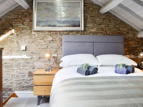 a bedroom with a large bed and a stone wall at The Cart House in Merthyr Cynog