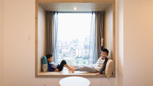 two children sitting on a window sill in front of a window at JR East Hotel Mets Premier Tokyo Bay Shinkiba in Tokyo