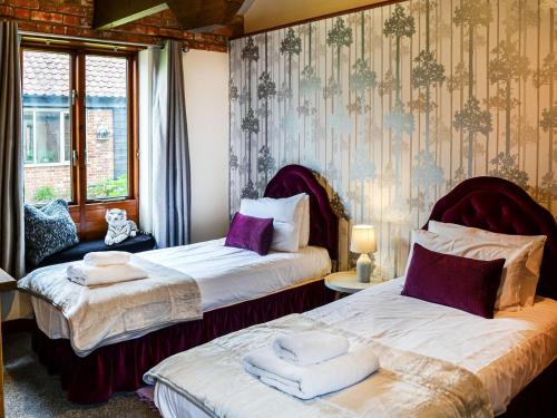 a bedroom with two beds with towels on them at Lodge Farm Barn in South Walsham