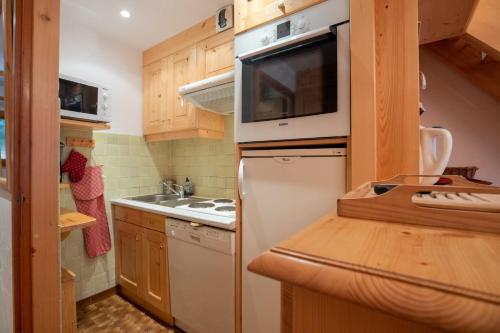 La cuisine est équipée d'un réfrigérateur blanc et d'un four micro-ondes. dans l'établissement Dryades G20, à Méribel