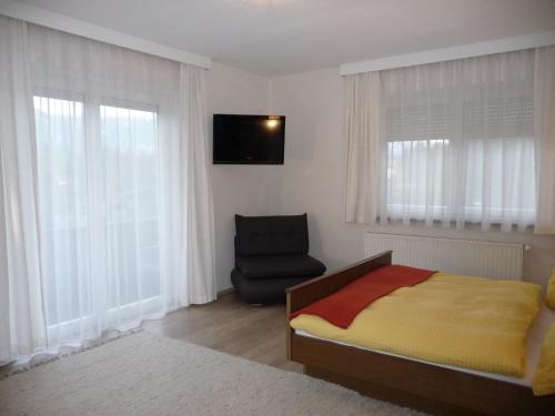 a bedroom with a bed and a chair and windows at Familiengasthof St. Wolfgang in Spittal an der Drau