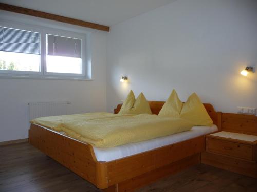 a bedroom with a wooden bed with yellow blankets and pillows at Familiengasthof St. Wolfgang in Spittal an der Drau