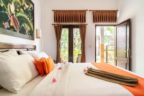 a bedroom with a large white bed with orange accents at Padanta Gili Trawangan in Gili Trawangan