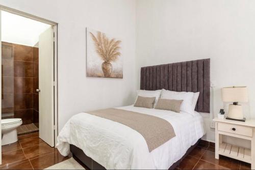a white bedroom with a bed and a bathroom at Suite Copal in Tecozautla