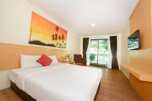 - une chambre avec un grand lit blanc et une télévision dans l'établissement Delta Chenang Resort, à Pantai Cenang