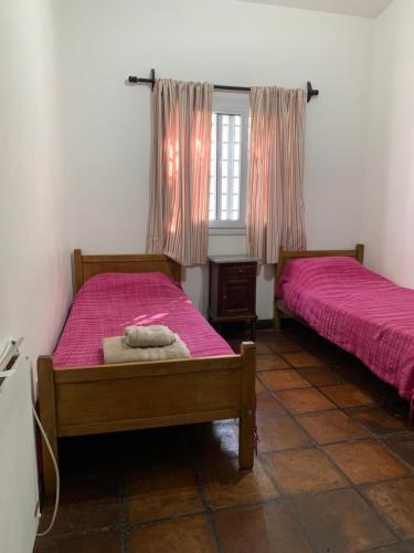 two beds in a room with pink sheets and a window at Casa Cafayate in Cafayate