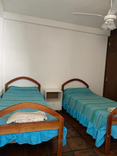 two beds in a room with two chairs at Casa Cafayate in Cafayate