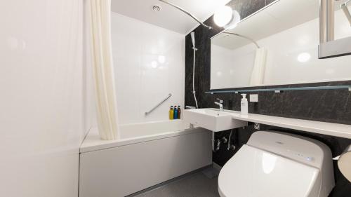 a white bathroom with a sink and a toilet at JR-East Hotel Mets Kawasaki in Kawasaki