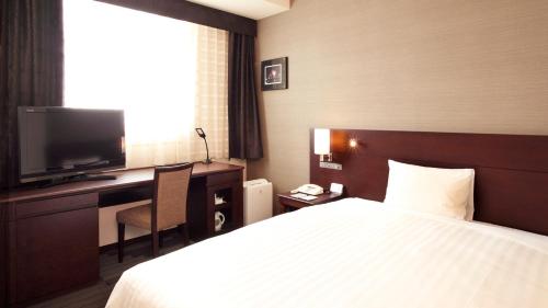 a hotel room with a bed and a desk and a television at JR-East Hotel Mets Yokohama Tsurumi in Yokohama