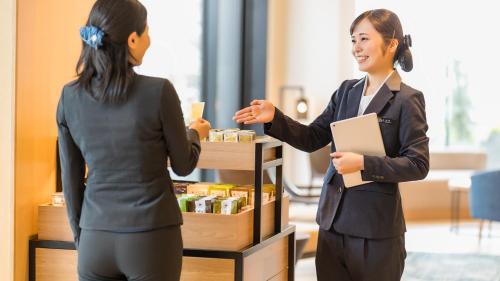 a woman shaking hands with a cash register at JR East Hotel Mets Premier Yokohama Sakuragicho in Yokohama