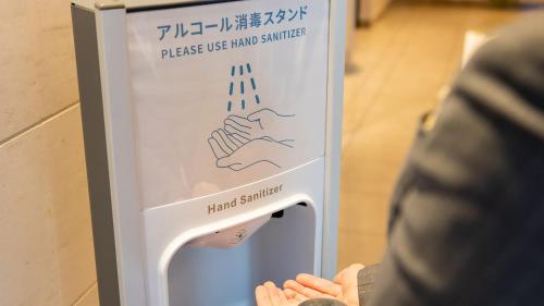 a person standing in front of a sign with a hand warmer at JR-East Hotel Mets Mizonokuchi in Kawasaki