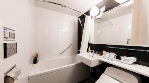 a bathroom with a sink and a toilet and a tub at JR-East Hotel Mets Urawa in Saitama