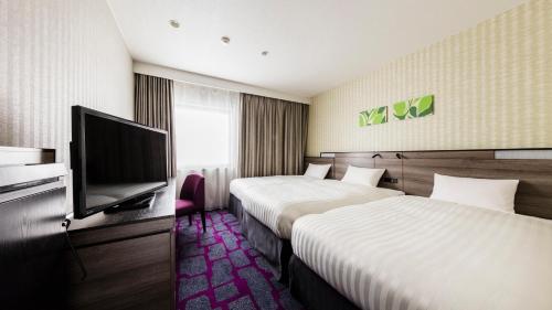 a hotel room with two beds and a flat screen tv at JR-East Hotel Mets Urawa in Saitama