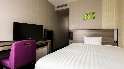 a hotel room with a bed and a purple chair at JR-East Hotel Mets Urawa in Saitama