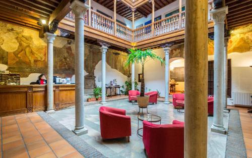 a large lobby with red chairs and a bar at Palacio de Santa Inés in Granada