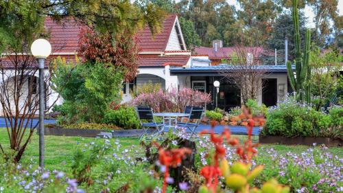 a house with a garden with chairs and flowers at Azalea Motel in Coonabarabran