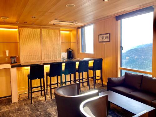 a kitchen with a bar with chairs and a couch at Hotel Shikinoyakata Hakone Ashinoko in Hakone