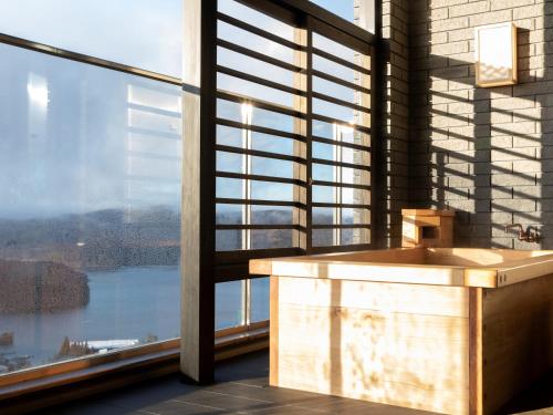 a bathroom with a tub in front of a large window at Hotel Shikinoyakata Hakone Ashinoko in Hakone