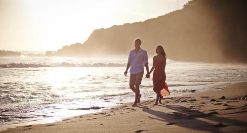 a man and a woman walking on the beach at Palm Hotel & Spa in Petite Île