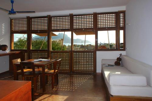 a living room with a table and a couch and windows at Paz Apartment in Mindelo