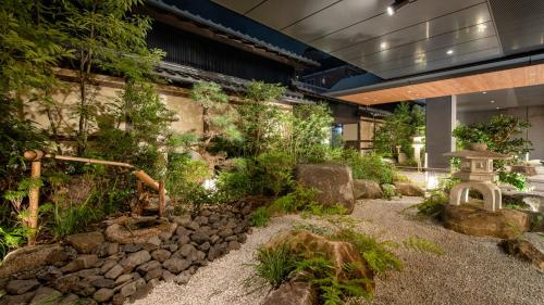 a garden with rocks and trees in a building at HOTEL UNIZO Kyoto Karasuma Oike in Kyoto