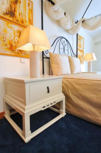 a white nightstand with a lamp on it next to a bed at Hotel Moliceiro in Aveiro