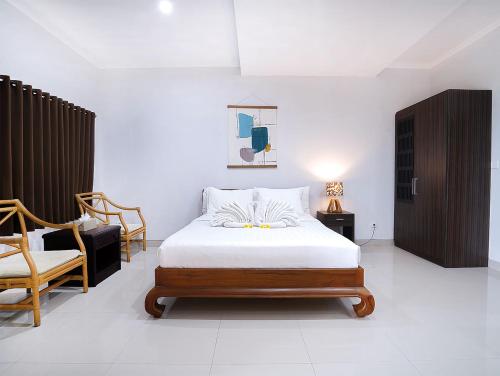 ein Schlafzimmer mit einem Bett und einem Stuhl in der Unterkunft Amanlane Suite Seminyak Managed by ARM Hospitality in Seminyak