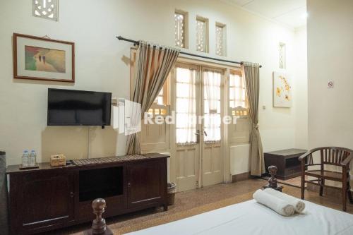 Zimmer mit einem Bett, einem TV und einem Fenster in der Unterkunft Monginsidi Guest House Syariah Malioboro Yogyakarta Mitra RedDoorz in Yogyakarta