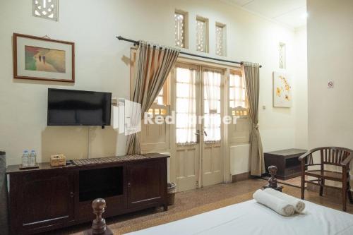 a room with a bed and a tv and a window at Monginsidi Guest House Syariah Malioboro Yogyakarta Mitra RedDoorz in Yogyakarta