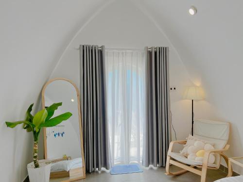 um quarto com um espelho, uma cadeira e uma janela em Malis Homestay em Trà Vinh