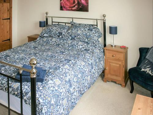 a bedroom with a bed with a blue and white comforter at Saswick Cottage in Elswick