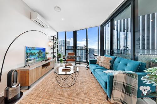 a living room with a blue couch and large windows at KozyGuru | Wentworth Point | 2 Beds stylish APT + Free Parking in Sydney