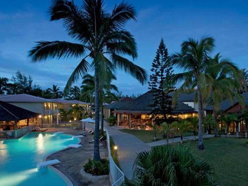 um resort com piscina e palmeiras à noite em Hotel Le Recif, Ile de la Reunion em Saint-Gilles-les Bains