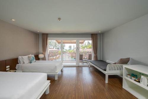 a bedroom with two beds and a balcony at Arinara Beach Resort Phuket - SHA Extra Plus in Bang Tao Beach