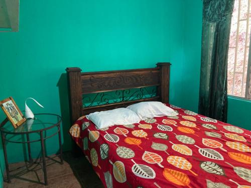 a bedroom with a bed with a red blanket and a table at Centro Ecológico Montaña Verde in Rivas