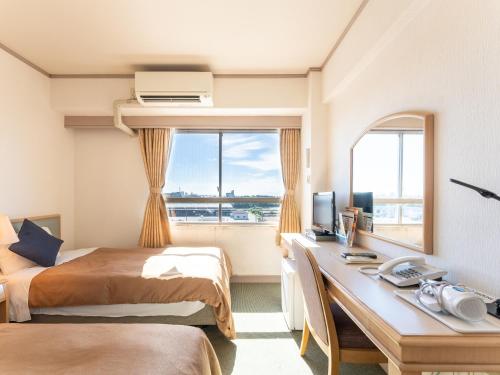 a hotel room with two beds and a desk and a window at Tabist Hotel Ginga Kisarazu in Kisarazu
