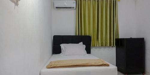 a bed with a black headboard and a green curtain at Citra Green House Syariah near Universitas Tulungagung in Tulungagung