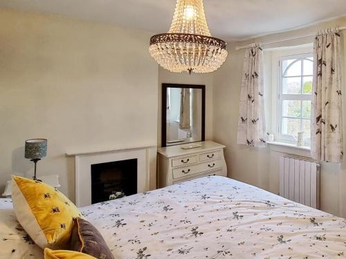 a bedroom with a bed and a chandelier at Plum Cottage in Castle Cary