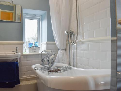 een badkamer met een bad, een wastafel en een douche bij Plum Cottage in Castle Cary