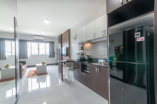 a kitchen with wooden cabinets and a black refrigerator at Eastpana Hotel - SHA Extra Plus in Si Racha