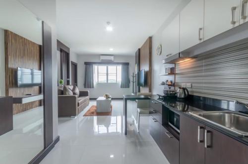 a kitchen with a sink and a living room at Eastpana Hotel - SHA Extra Plus in Si Racha
